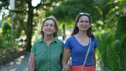 Happy mother and adult daughter smiling and laughing outside