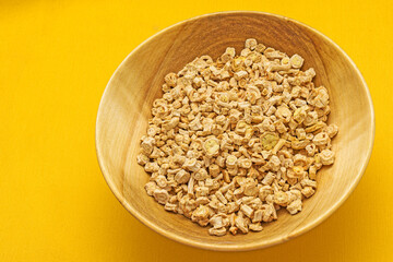Wooden plate with dried pieces of parsley root on a yellow background close-up