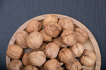 Nuts on a wooden plate. Group of walnuts on a black background. Walnut on black top view.