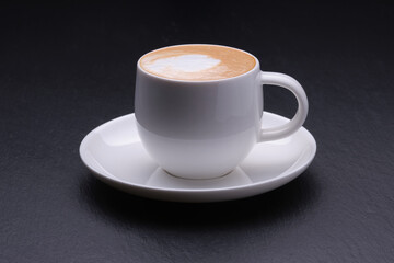 White cup of coffee with a saucer on a black background side view. Coffee with milk on a black background close up.hh
