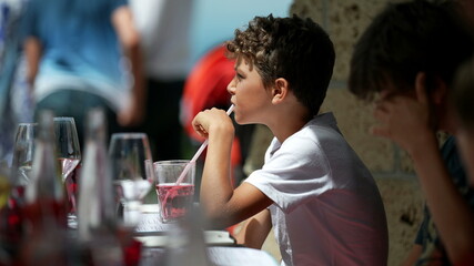 Child drinking from glass water with straw at restaurant