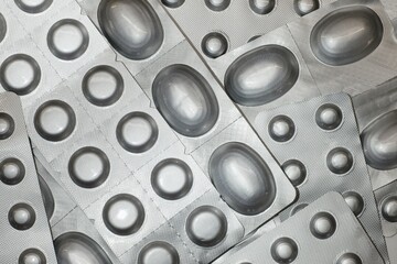 Different pills blisters as a silver textured background