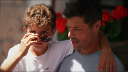 Candid child with father together, small boy wearing sunglasses with arm around dad