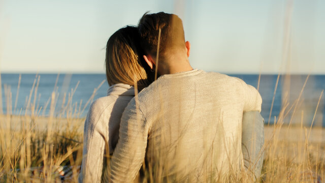 Ragazza e ragazzo di spalle sulla spiaggia a San Valentino al tramonto