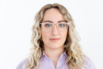 Obraz premium Portrait of a young woman with wavy blonde hair, looking into camera. Large glasses for vision. Shirt is light purple. White background.