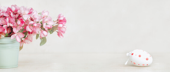 Happy Easter. Easte egg on spring festive blooming with pink white flowers fruit tree branches in small vase against tender pastel background. Fresh floral background with copy space
