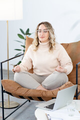 Blonde woman meditates sitting in a chair in the lotus position. Rest from the hard psychological...