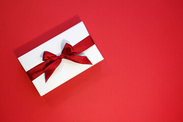 Valentines Day banner. White gift box with red ribbon on red background. Flat lay, top view. Love and romance concept.