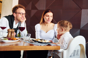 Young guy, woman and little boy. Indoors of new modern luxury restaurant