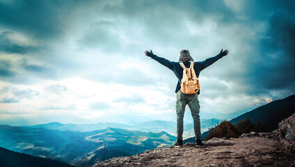 Happy man with open arms standing on the top of mountain - Hiker with backpack celebrating success...
