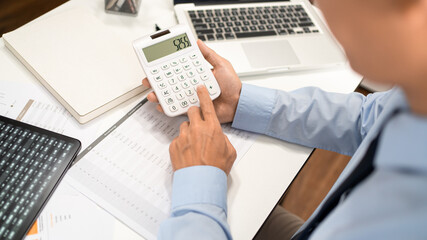 Working Man Conept The male officer sitting at his desk, holding the calculator, and pressing it