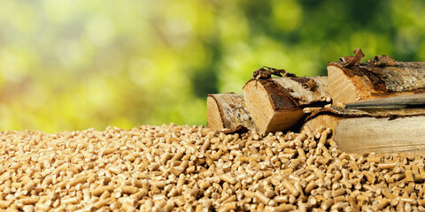 biomass - wood pellets and birch firewood on green leaf background. renewable energy - obrazy, fototapety, plakaty