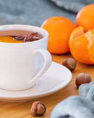 A cup of hot tea with anise star. Tea served in bed. Tangerines and hazelnuts.