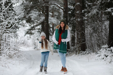 Young family for a walk. Mom and daughter are walking in a winter park.