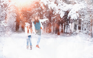 Young family for a walk. Mom and daughter are walking in a winter park.