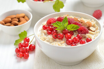 Tasty oatmeal porridge with raspberries, nuts and red currant