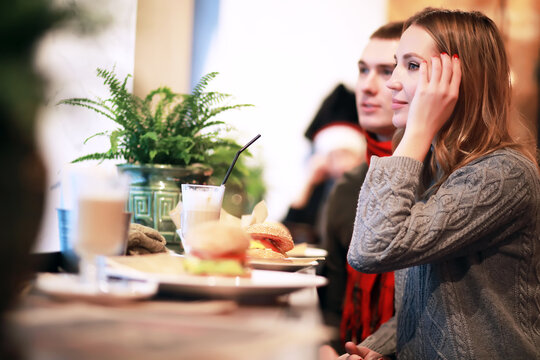 Couple In A Restaurant Or Diner Eating A Hamburger And Chicken Wings Flirting The While, Shot With Available Light, Very Selective Focus