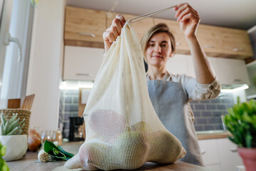 Young woman tie the organic cotton reusable produce bag with vegetables - Powered by Adobe