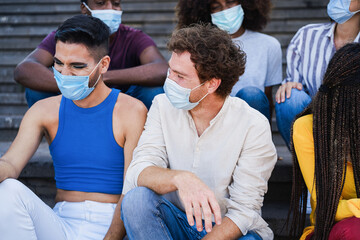 Obraz premium Young diverse people laughing together wearing safety mask outdoor in the city - Focus on center man face