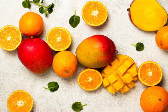 Fresh oranges and mangoes near leaves