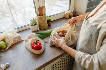 Young woman holding the organic cotton reusable produce bag with vegetables and fruits