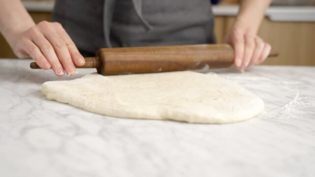 Anonymous woman rolling dough for pizza