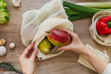 Young woman holding reusable cotton produce bags for shopping