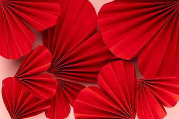 Bright red hearts of folded of chinese paper fans as romantic Valentine day background, texture, closeup, top view.