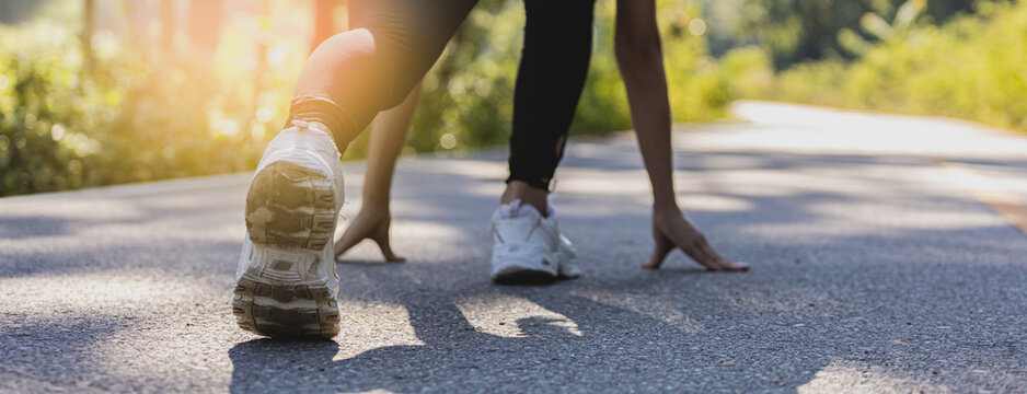 Woman sitting and getting ready to start jogging, she is running in a park where many people come to jogging in the morning and evening, running is a popular activity. Health care concept with jogging