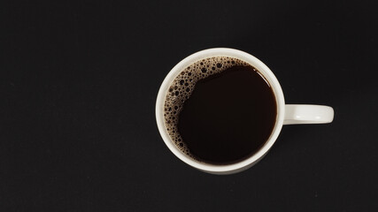 Hot coffee in white mug isolated on black background. top eye view