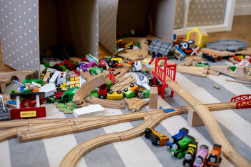 Toys are scattered around the room. Wooden rails and a steam locomotive. Defocus.