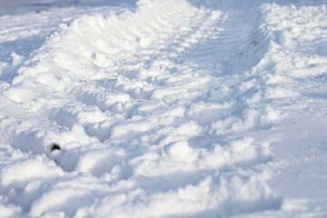 Large wheel trail with deep tread in the snow, close-up, selective focus.