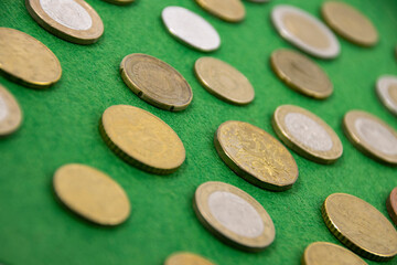 Collection of European coins on a green cloth as a background, selective focus.