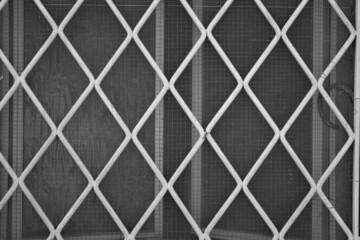 evocative black and white image of rhombus shaped white iron grate texture 