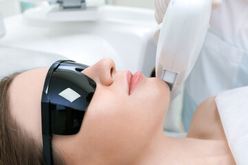 Laser hair removal of the mustache and chin of a young beautiful woman. Depilation on the face.