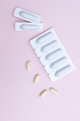 Gynecological medicines for women's health in form of suppository, capsules on pink background.