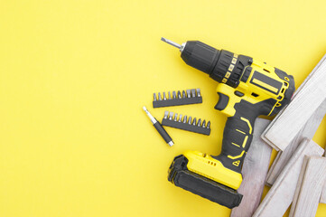 The yellow-black screwdriver on a yellow background, screws, a set of bits.