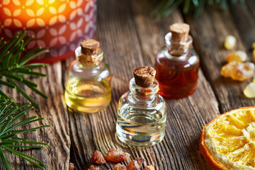 Essential oil bottles with myrrh resin, dried orange, fir and candle