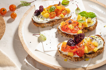 Italian bruschettas with roasted tomatoes, cream cheese, pineapple slices and herbs on a kitchen countertop. Prepared to serve