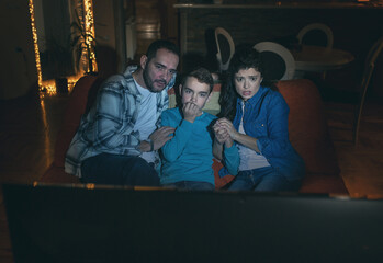 Obraz premium Father, mother and son looking horror movie at home