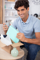 handsome young man opening box with parcel at home