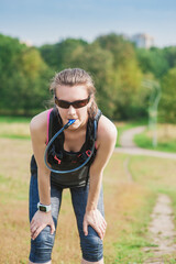 Beautiful fitness woman drinking water from the tube of hydropack