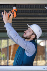 glazier using cordless drill on window frane