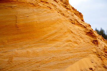 Textural sand, with  relief surface, multi-colored layers and different in size of granules, in outdoor sand career, after mining ore and sand for construction.