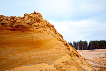 Fototapeta na wymiar Textural sand, with relief surface, multi-colored layers and different in size of granules, in outdoor sand career, after mining ore and sand for construction.