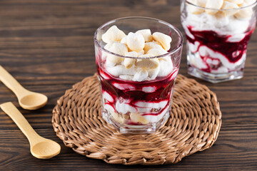 Homemade dessert with aquafaba meringue, coconut cream and cherries in glasses on a wooden table. Sugar, lactose free, vegan.