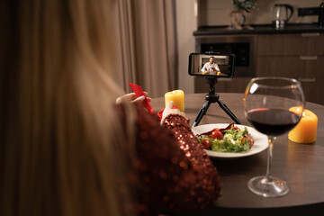 Online date. A young woman makes a video call to a friend using an app on her smartphone. candlelight dinner at a distance. Online dating concept.