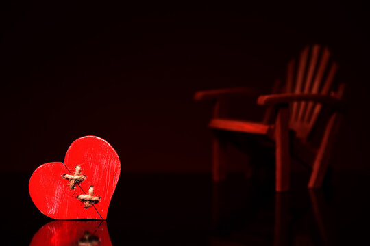 Tekstura tła.zranione serce, w tle pusty fotel. Anty walentynki, kompozycja na dzień singla. tło na życzenia dla niej, lub dla niego. textura na tapetę na ciemnym tle.