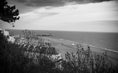 View out to the sea with hte beach and a curved apartment building, as seen from the top of the Folkestone cliffs. Black and white, overcast day.