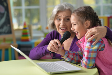 Portrait of grandmother and granddaughter singing karaoke
